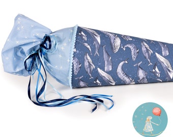 May include: A blue and white fabric cone-shaped bag with a blue ribbon and a whale print. The bag is tied with a blue ribbon and has a white cross pattern on the fabric.