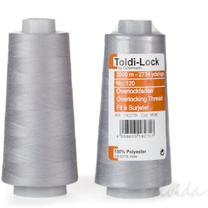 Könnte beinhalten: Zwei Spulen silbergrauen Overlockgarns, jede mit einem Etikett mit der Aufschrift "Toldi-Lock by Gütermann" und Details wie "2500 m - 2734 yds/vgs", "No. 120", "Overlockfaden", "Overlocking Thread", "Fil à Surjeter", "Art. 742279 Col. 9540" und "100% Polyester CA 02776, India".