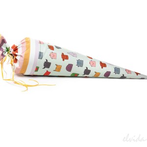 May include: A cone-shaped fabric bag with a yellow ribbon tie. The bag is decorated with a pattern of colorful cartoon faces.