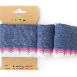 Könnte beinhalten: Eine Rolle blauer und weißer Strickstoff mit rosa gewelltem Saum. Der Stoff ist mit "ALB Stoffe" und "hamburgerliebe by Susanne Firmenich" sowie "Made in Germany" beschriftet.