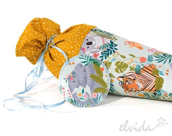 May include: A light blue and white fabric cone with a colorful jungle animal print. The cone is decorated with a yellow and white polka dot fabric bag and a round fabric patch with a gray elephant and floral design. The cone has a blue ribbon tied around it.