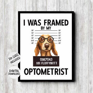 May include: A framed print with a dog wearing glasses, resembling a mugshot. The text reads "I WAS FRAMED BY MY OPTOMETRIST" with height measurements in feet and inches. The dog's mugshot reads "0987043 MR FLUFFYBUTT".
