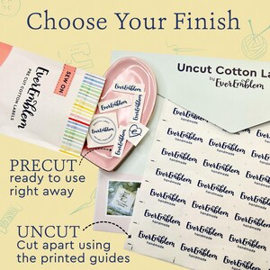 May include: A collection of EverEmblem cotton labels including a package of pre-cut sew-on labels, a pink dish containing loose labels, and a sheet of uncut cotton labels with printed guides. The text reads Choose Your Finish and Uncut Cotton Labels.