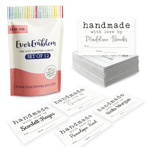 May include: A set of 12 pre-cut cotton labels in a white and pink plastic-free compostable pouch. The labels are white rectangles with black text reading handmade with love by followed by a name, with lines for For and Date. Brand is EverEmblem.
