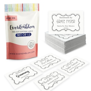 Può includere: Una confezione di etichette in cotone pretagliate con la scritta "EverEmblem" e "SET OF 12". Vengono visualizzate diverse etichette bianche con testo nero, ciascuna con un bordo decorativo e le parole "Handmade By" e un nome, una località e l'anno 2026.