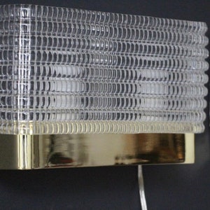 Puede incluir: Un par de apliques de pared de lat&oacute;n con pantallas de vidrio transparente texturizado. Las apliques tienen un dise&ntilde;o simple y moderno y ser&iacute;an una gran adici&oacute;n a cualquier hogar.