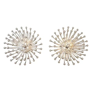 May include: A pair of silver-colored stud earrings. Each earring features a central sphere with radiating, thin, wire-like structures ending in small, round beads, creating a spiky, starburst design. The earrings have a polished, metallic finish.