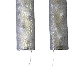 May include: A pair of clear, textured glass wall sconces, cylindrical in shape. Each sconce features a rectangular metal accent at the top and bottom, with a wire extending from the base. The glass has a woven pattern.