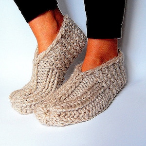 May include: A pair of beige knitted slipper socks with a cable knit pattern.