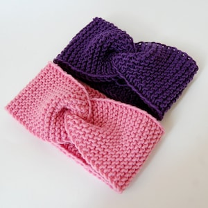 May include: Two knitted headbands, one pink and one purple. The headbands are made with a simple knit stitch and have a twisted design.