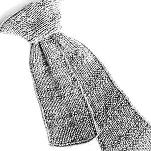 May include: A light gray knitted necktie featuring a textured stitch pattern. The tie is constructed with a wide blade and a narrower neck band, showcasing a consistent yarn weave throughout the entire length of the accessory.