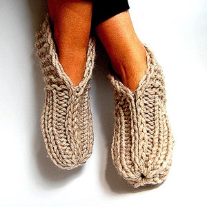 May include: A pair of beige knitted slipper socks with a cable knit pattern.