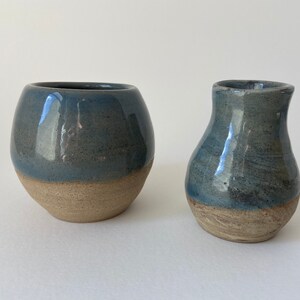 May include: Two ceramic vases, one round and one pear-shaped, both with a blue glaze and a brown base.