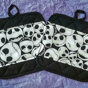 May include: Two black and white quilted pot holders featuring a pattern of Jack Skellington's face from The Nightmare Before Christmas.