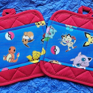 May include: Two red quilted pot holders with blue fabric panels featuring a variety of Pokemon characters, including Pikachu, Jigglypuff, and Charmander.
