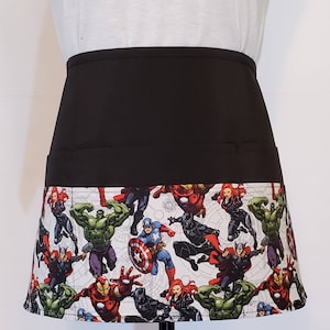 May include: Black apron with a white and black patterned bottom featuring various Marvel superheroes including Iron Man, Captain America, Hulk, and Black Panther.