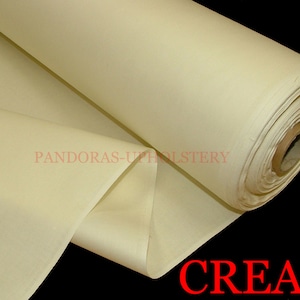 Può includere: Un rotolo di tessuto per tappezzeria di colore crema. Il tessuto è liscio e ha una leggera lucentezza. Il tessuto è arrotolato e legato con uno spago marrone.