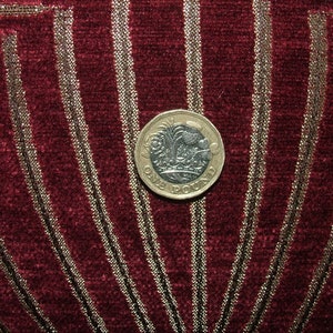 May include: A silver British one pound coin with the inscription "ONE POUND" on a red and gold fabric background.