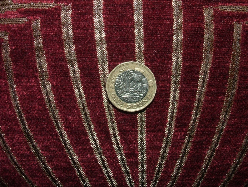 May include: A silver British one pound coin with the inscription "ONE POUND" on a red and gold fabric background.