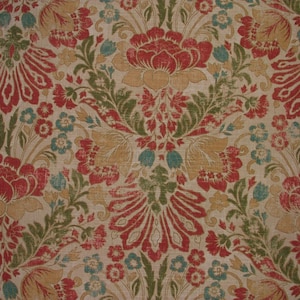 May include: A beige fabric with a repeating floral pattern in shades of red, green, and gold. The pattern features large, stylized flowers with intricate details.