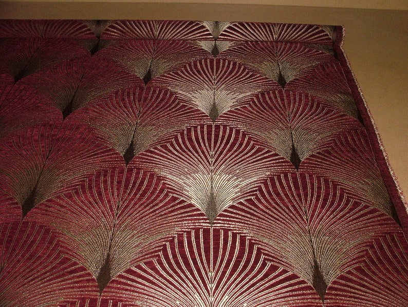May include: Red fabric with a gold and brown geometric pattern of overlapping fan shapes.