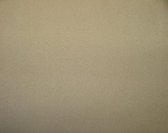 Op de afbeelding: Een close-up van een getextureerd, beige oppervlak. Het oppervlak heeft een subtiele, korrelige uitstraling, met een consistente kleur en textuur over het hele frame. De belichting is gelijkmatig, waardoor de fijne details van het materiaal worden benadrukt.