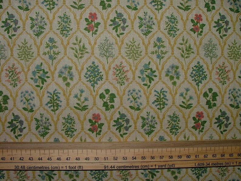 May include: Fabric featuring a repeating floral pattern with pink, blue, and green flowers. The flowers are set against a cream background with a gold trellis design. Suitable for craft projects. Measurements are in centimetres.
