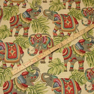 May include: Beige fabric with a repeating pattern of colorful elephants with intricate designs. The elephants are surrounded by green leaves.