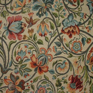 May include: Close-up of a floral tapestry with a cream background. The design features stylized flowers in shades of red, blue, and orange, with green leaves and dark gray stems. Small bird motifs are also incorporated into the pattern.