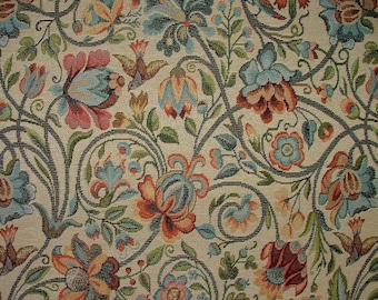 May include: Close-up of a floral tapestry with a cream background. The design features stylized flowers in shades of red, blue, and orange, with green leaves and dark gray stems. Small bird motifs are also incorporated into the pattern.