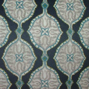 May include: Close-up of a patterned fabric with a repeating design. The pattern features a dark navy blue background with light gray and teal-colored floral-like shapes. The shapes are outlined in teal and have small teal accents.