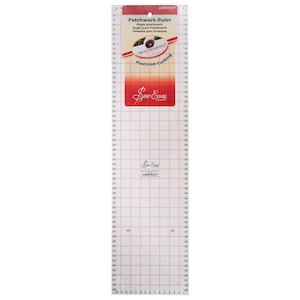 May include: A white patchwork ruler with red markings and a grid pattern. The ruler is labelled "Patchwork Ruler" and "Precision Cutting". The ruler is made by Sew Easy and is laser cut.