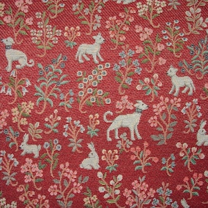 May include: Red fabric with a repeating pattern of white lambs, rabbits, and floral designs. The fabric has a textured, woven appearance.