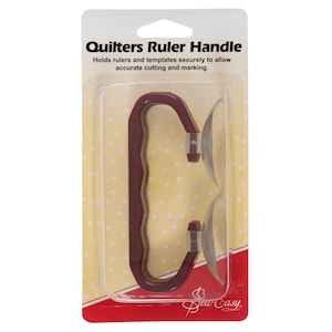 May include: A red plastic quilting ruler handle with two suction cups. The handle has a textured grip and the packaging says "Quilters Ruler Handle" and "Sew Easy".
