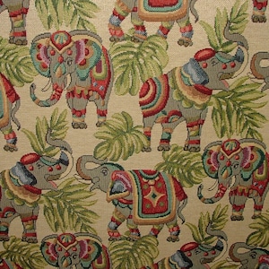 May include: A beige fabric with a repeating pattern of colorful elephants with intricate designs. The elephants are surrounded by green leaves.
