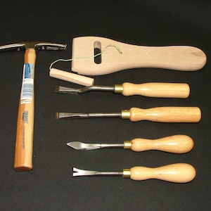 May include: A set of leather working tools including a hammer, a wooden mallet, and four chisels with wooden handles.