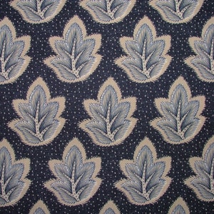 May include: A dark blue fabric with a repeating pattern of stylised beige leaves with blue accents. The leaves have a textured, almost fuzzy appearance.