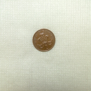 May include: A two pence coin from the United Kingdom, featuring a copper-coloured design of the Welsh dragon.