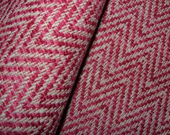 Puede incluir: Primer plano de una tela texturizada con un patrón de espiga tejido. La tela presenta una combinación de hilos blancos y rosas vibrantes, creando un diseño visualmente dinámico. El material parece estar doblado, mostrando la textura y profundidad del tejido.