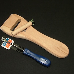 Puede incluir: Una herramienta de madera con mango y un hueco para una pieza de madera más pequeña. También se muestra una herramienta azul y plateada con mango negro.