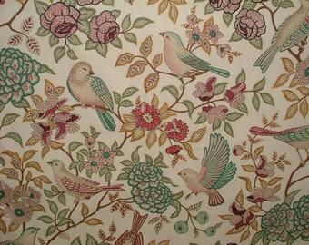 May include: A beige fabric with a repeating pattern of pink and green flowers, leaves, and birds. The birds are a variety of colors, including blue, green, and pink.