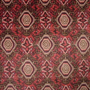 May include: Close-up of a patterned fabric with a repeating geometric design. The pattern features a combination of red, brown, and beige colors. The design includes diamond and octagon shapes, creating a textured appearance.