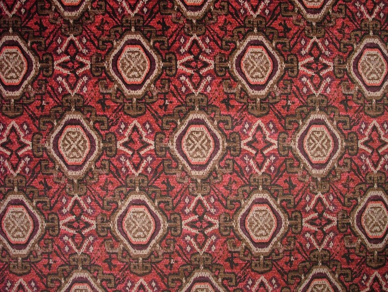 May include: Close-up of a patterned fabric with a repeating geometric design. The pattern features a combination of red, brown, and beige colors. The design includes diamond and octagon shapes, creating a textured appearance.