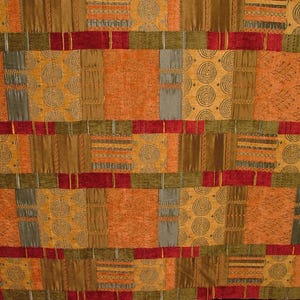 Può includere: Tessuto con un design patchwork con quadrati nei toni dell'arancione, marrone e oro. I quadrati sono separati da fasce rosse, verdi e grigie. Alcuni quadrati presentano motivi a spirale o dettagli strutturati.