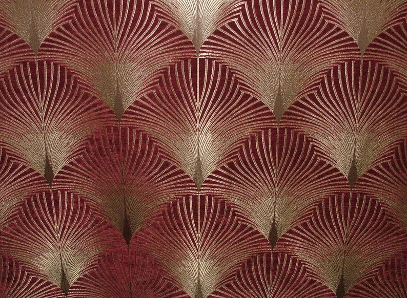 May include: A red fabric with a gold geometric pattern of overlapping fan shapes.