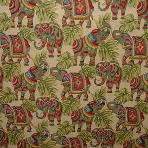 May include: A beige fabric with a repeating pattern of colorful elephants with intricate designs. The elephants are surrounded by green leaves.