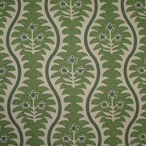 May include: A repeating pattern with green floral and leaf motifs on a beige background. The design includes curved vertical lines framing the floral elements, creating a symmetrical pattern. The flowers have white petals. The pattern is decorative.