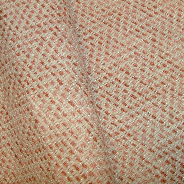 Puede incluir: Primer plano de una tela tejida con aspecto texturizado. La tela presenta un patrón repetitivo de pequeños bloques rectangulares en tonos crema y rosa coral, creando un diseño sutil en forma de cuadrícula. La tela está ligeramente arrugada.
