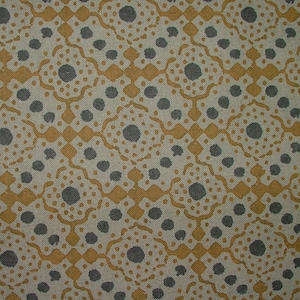 May include: Close-up of a fabric with a repeating pattern. The design features a cream-coloured background with a repeating pattern of grey circles and mustard-yellow geometric shapes. The fabric has a textured appearance.