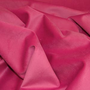 May include: A close-up of a soft, pink fabric with a smooth texture. The fabric is folded and draped, creating a luxurious and elegant look.